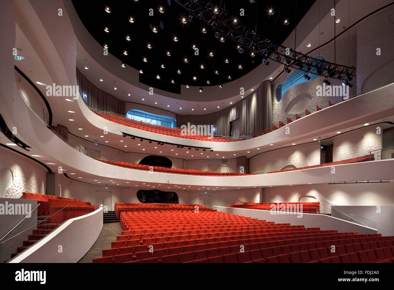 Sala principale con posti a sedere rossi contro la curvatura pareti bianche e balconi. Musikkens Hus Aalborg, Aalborg, Danimarca. Architetto: Coop Foto Stock