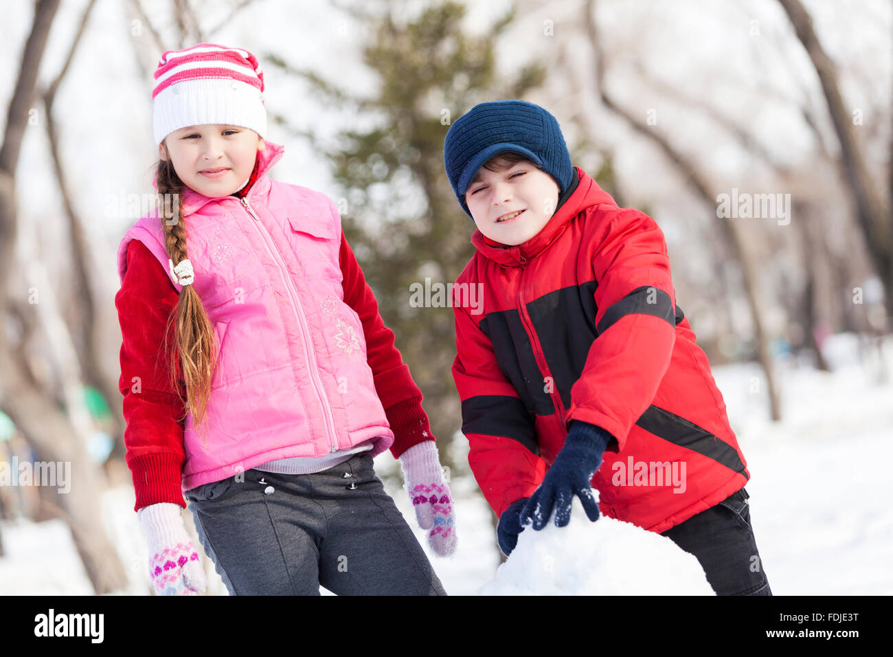 Carino un ragazzo e una ragazza la costruzione di pupazzo di neve in inverno park Foto Stock