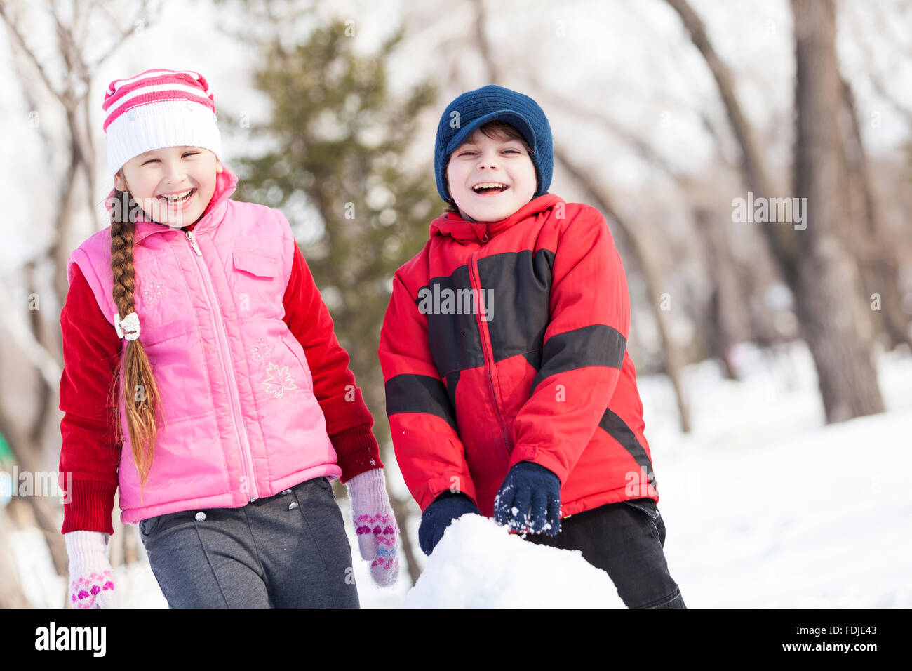 Carino un ragazzo e una ragazza la costruzione di pupazzo di neve in inverno park Foto Stock