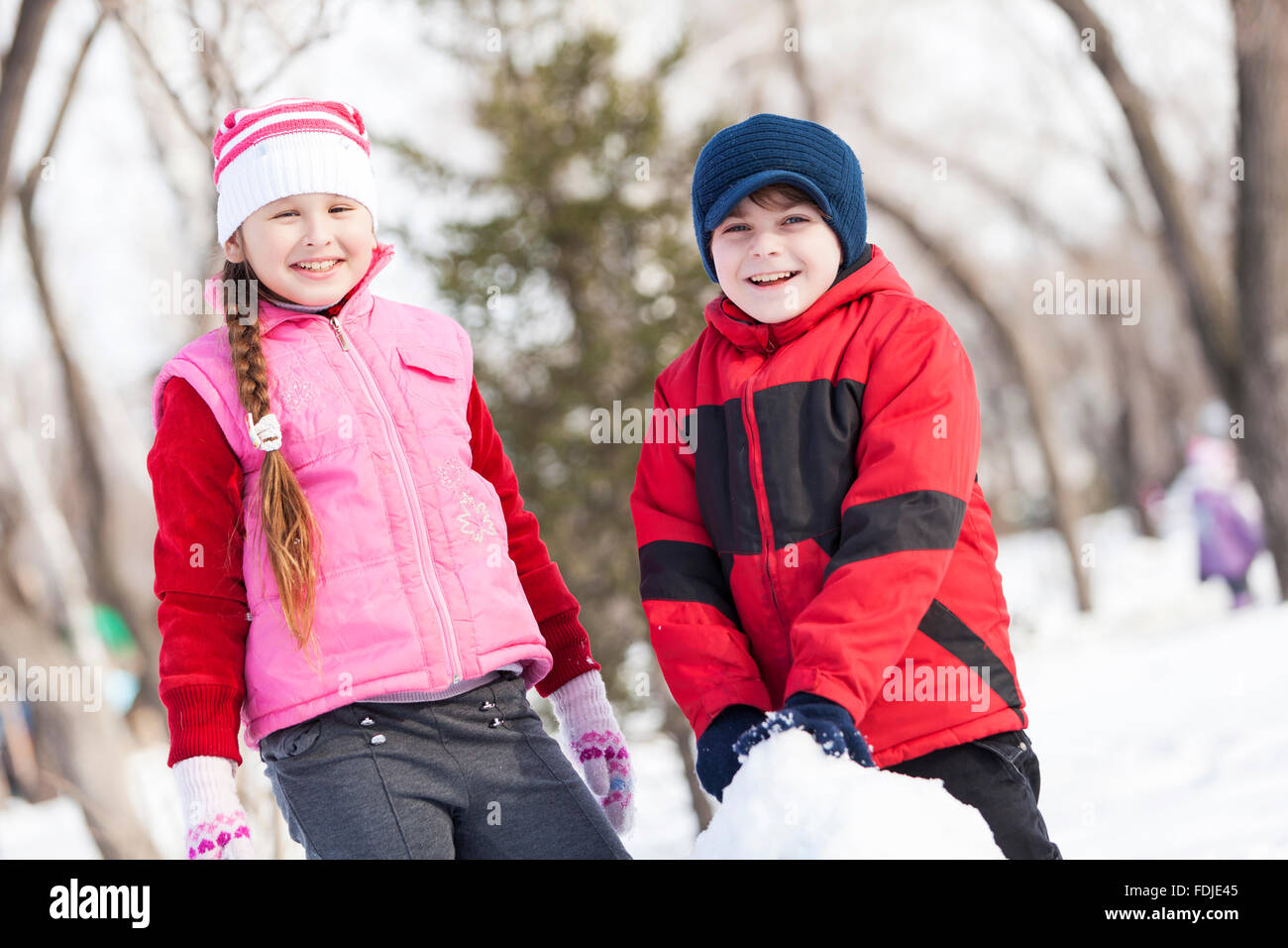 Carino un ragazzo e una ragazza la costruzione di pupazzo di neve in inverno park Foto Stock