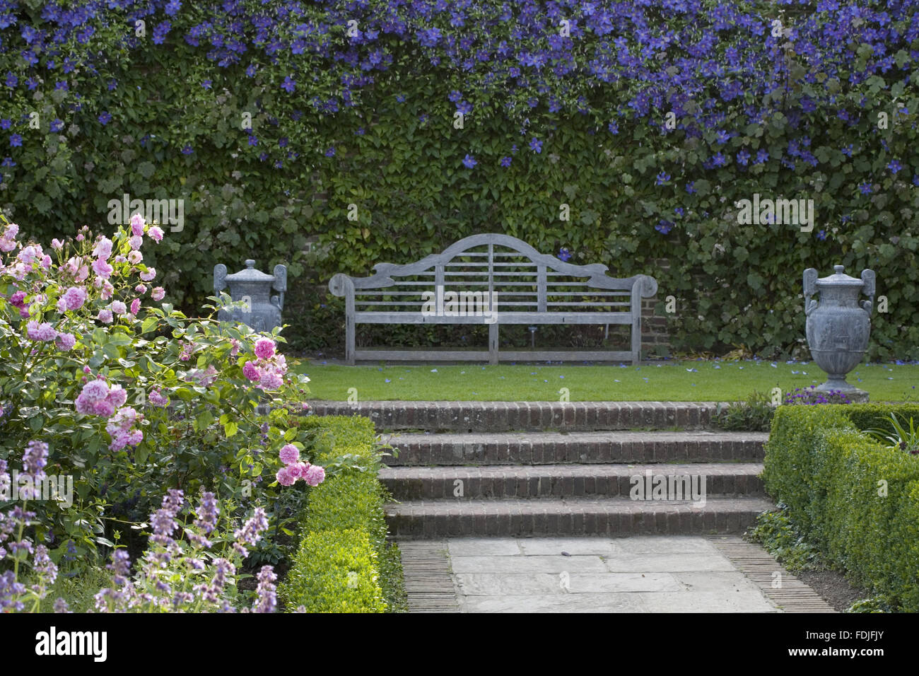 La clematide 'Perle d'Azur' dietro un banco di Lutyens nel Giardino di Rose presso il castello di Sissinghurst giardino, vicino a Cranbrook, Kent. Foto Stock