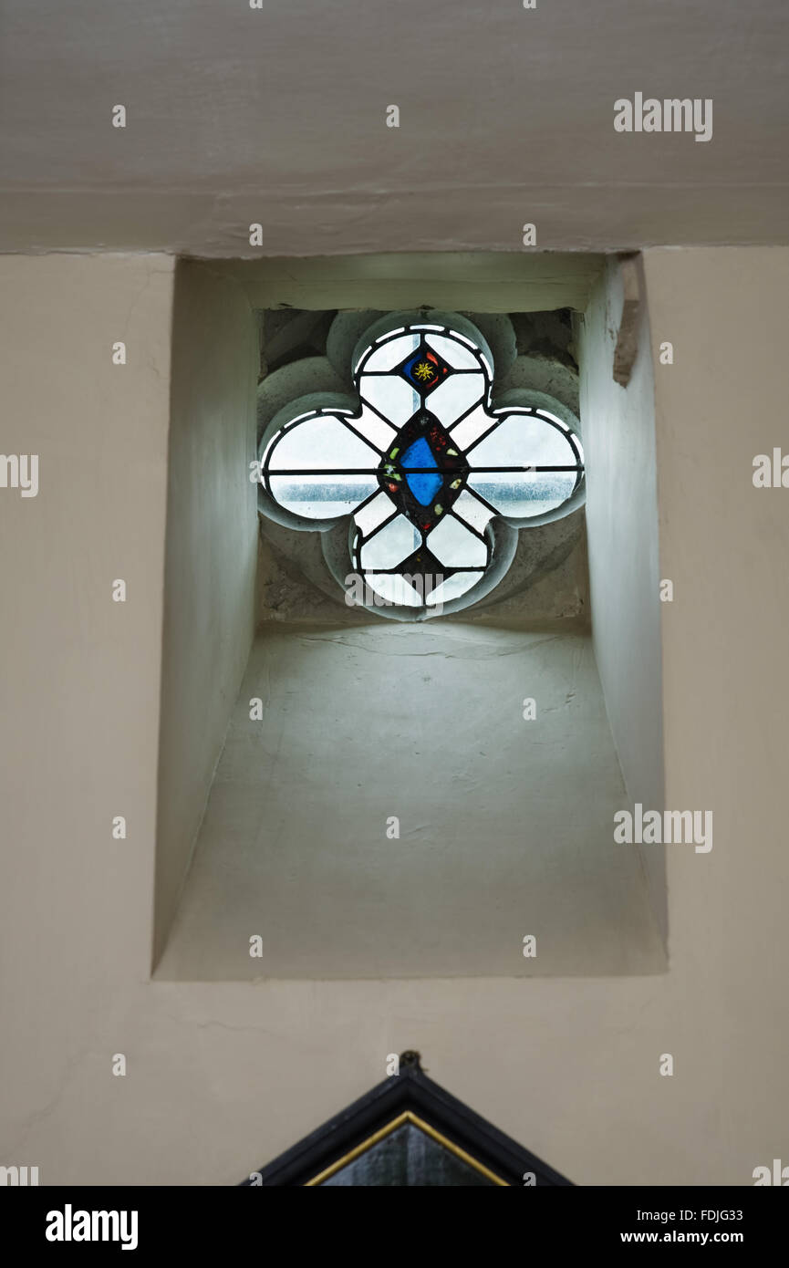 Il vetro macchiato quatrefoil finestra in una rientranza nella cappella a Buckland Abbey, Yelverton, Devon. La cappella è stata restaurata nel 1917 sul sito dell'abbazia di alto altare e fu riconsacrata a San Benedetto e della Beata Vergine Maria. Foto Stock