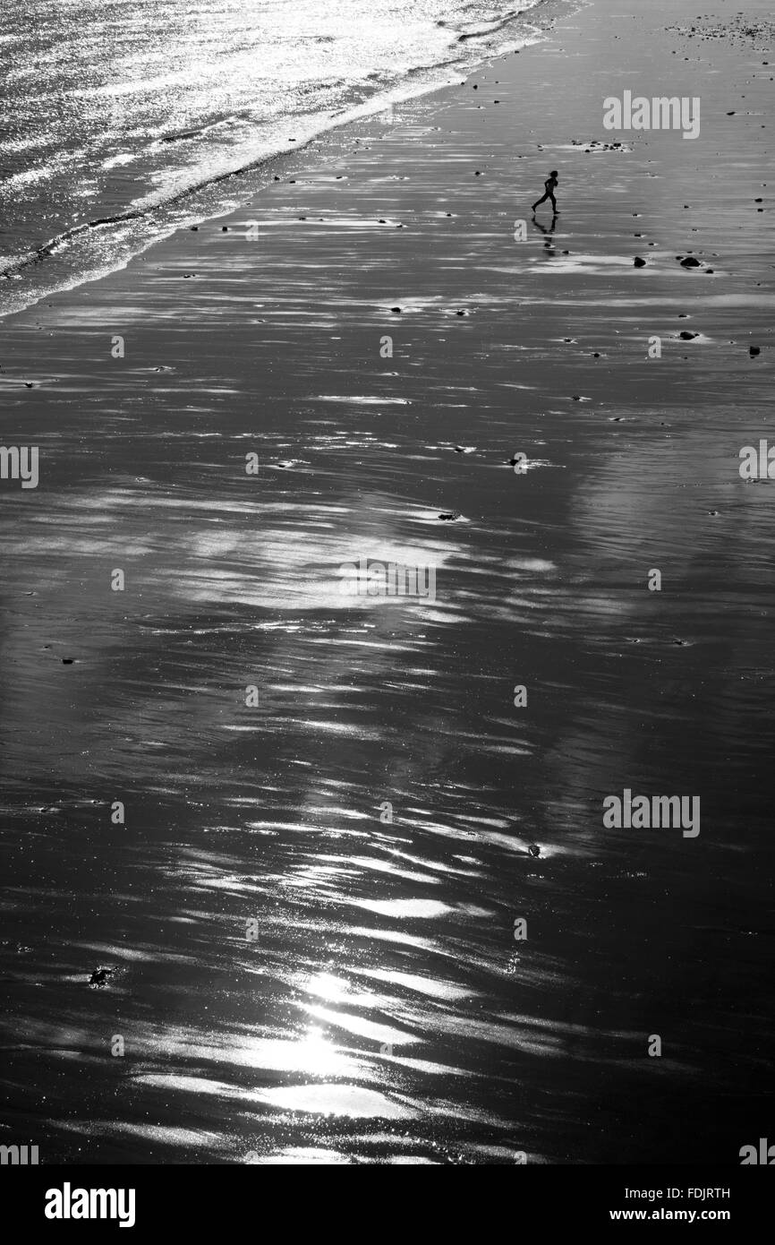 Persona corre attraverso Penarth beach, Cardiff, Galles Foto Stock