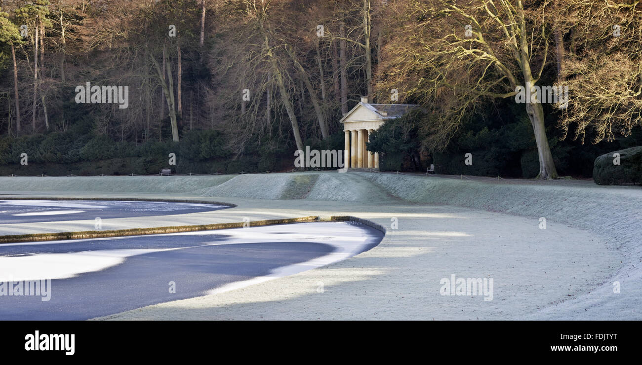 Veduta invernale del tempio di pietà visto oltre il Half-Moon stagno, a Studley Royal acqua da giardino, North Yorkshire. I giardini sono stati creati nel 1716 da John Aislabie e proseguito da suo figlio Guglielmo nel seguito del XVIII secolo. Foto Stock