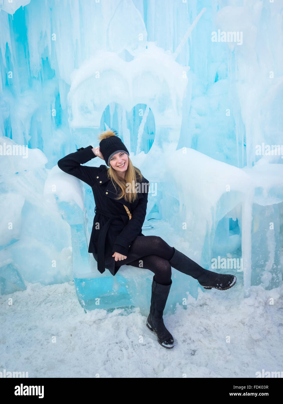 Una bella ragazza bionda si siede su un trono scolpito dal ghiaccio presso il castello di ghiaccio in Hawrelak Park, Edmonton, Alberta, Canada. Foto Stock