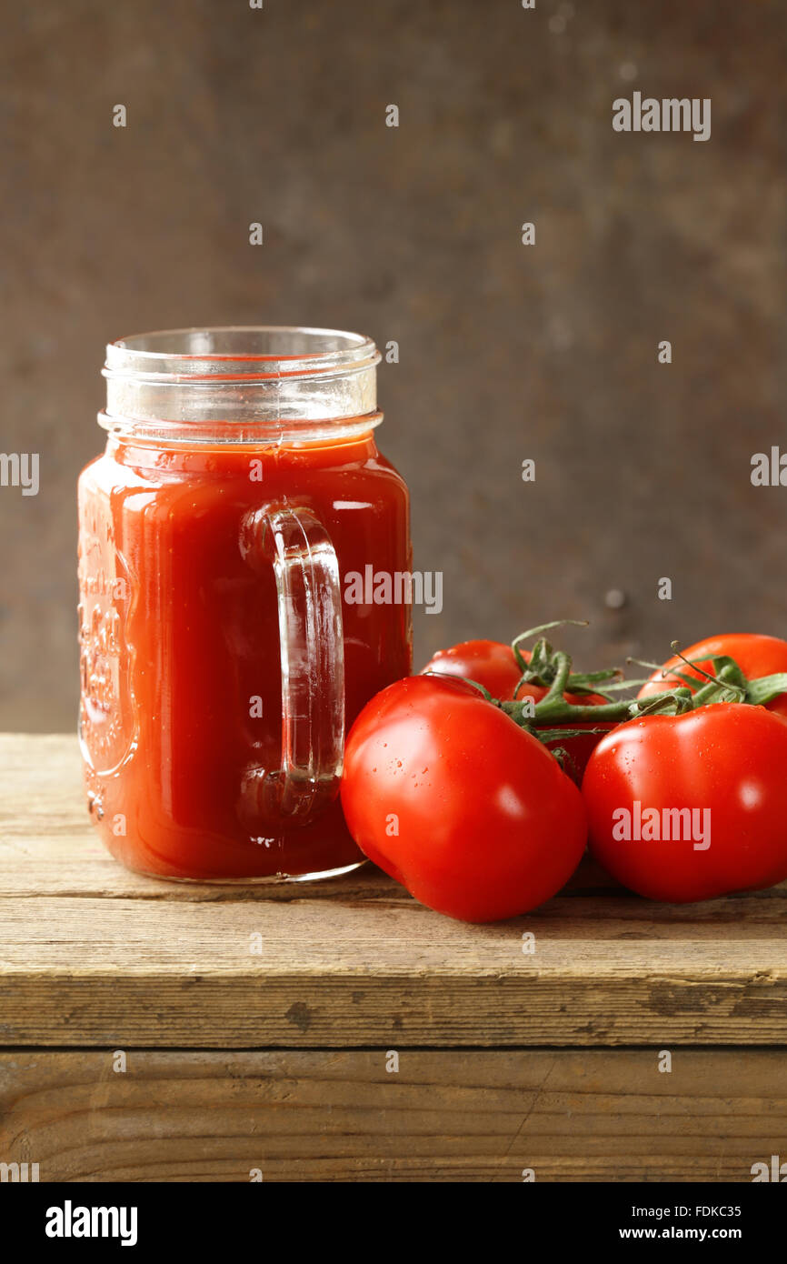Il pomodoro fresco di succo in un vasetto di vetro sul tavolo Foto Stock