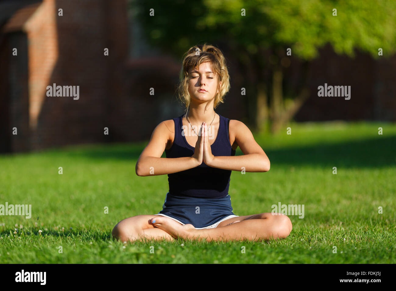 Ragazza giovane e carina facendo esercizi yoga nel parco Foto Stock