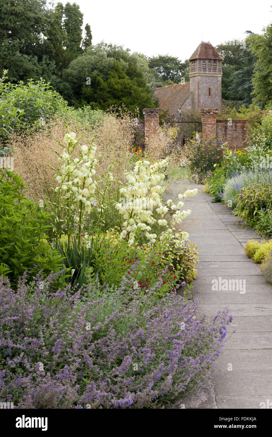 Il confine erbacee in il giardino murato nel mese di luglio a Hinton Ampner, Hampshire. Chiesa di tutti i santi a distanza non è il National Trust. Foto Stock