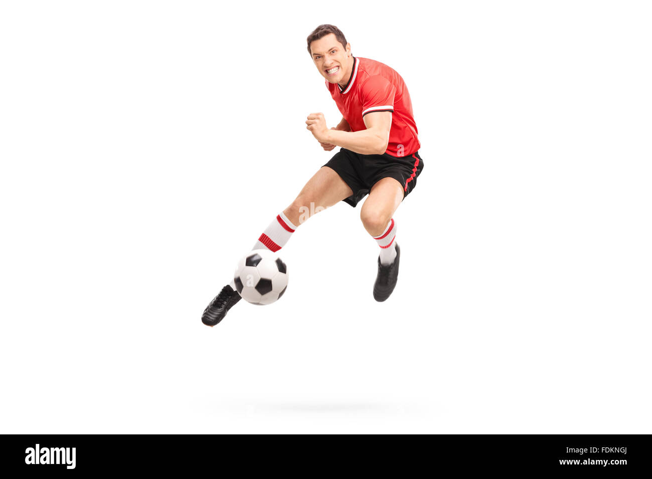 Studio shot di un giovane giocatore di calcio calcio di un pallone shot a mezz aria isolata su sfondo bianco Foto Stock