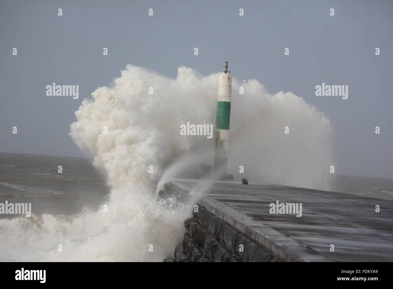 Aberystwyth Wales UK, 2016 onde enormi pilotato da gale force venti continuano a pastella le difese del mare della costa gallese Foto Stock