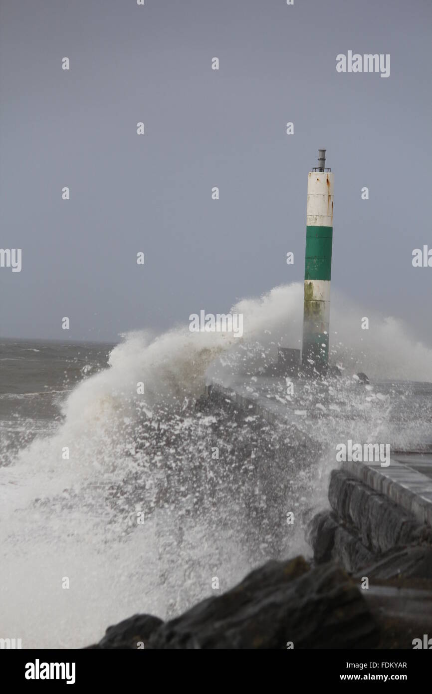 Aberystwyth Wales UK, 2016 onde enormi pilotato da gale force venti continuano a pastella le difese del mare della costa gallese Foto Stock