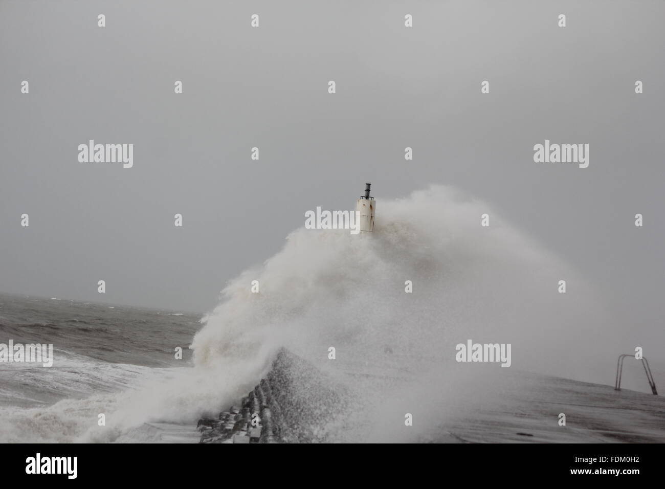 Aberystwyth Wales UK 2016, onde enormi pilotato da gale force venti continuano a pastella le difese del mare della costa gallese Foto Stock
