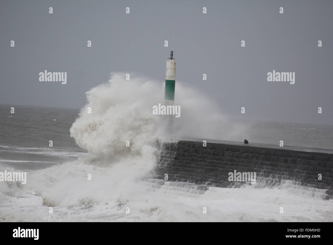Aberystwyth Wales UK 2016, onde enormi pilotato da gale force venti continuano a pastella le difese del mare della costa gallese. Foto Stock