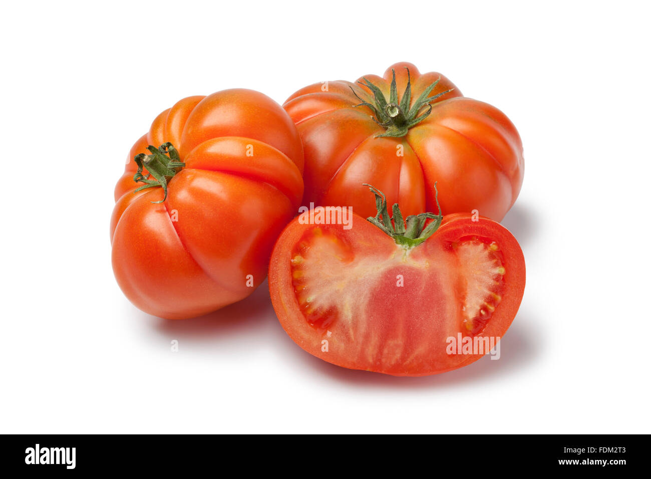 Intero e metà organic Coeur de boeuf pomodori su sfondo bianco Foto Stock
