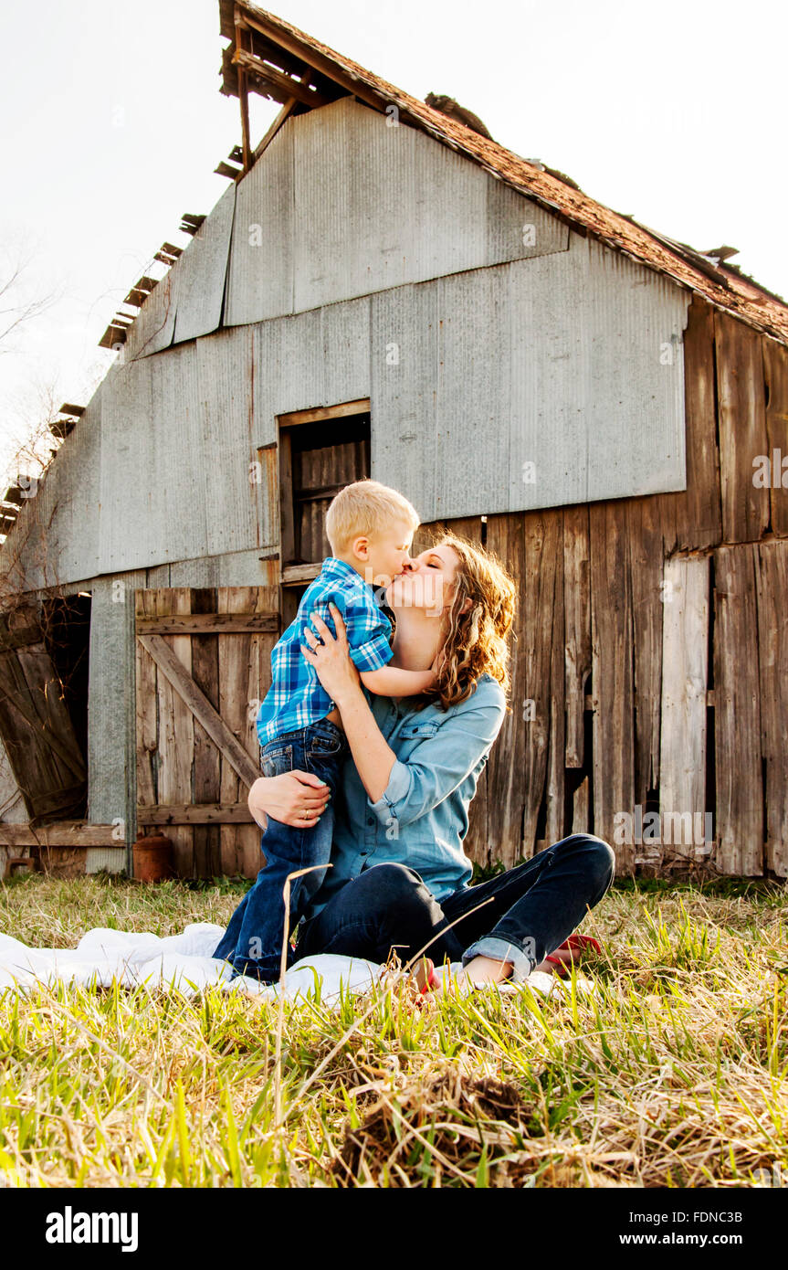 Madre e figlio condividi kiss e abbraccio contro lo sfondo del granaio Foto Stock