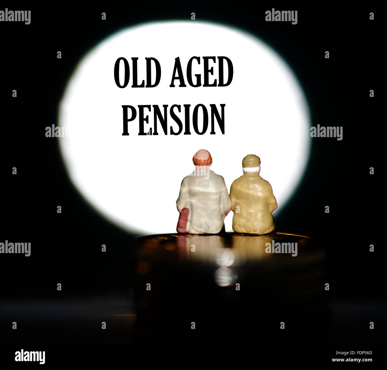 Statuetta in miniatura pensionati seduti sulle monete di fronte un faretto che mostra le parole rendita di vecchiaia concept Foto Stock