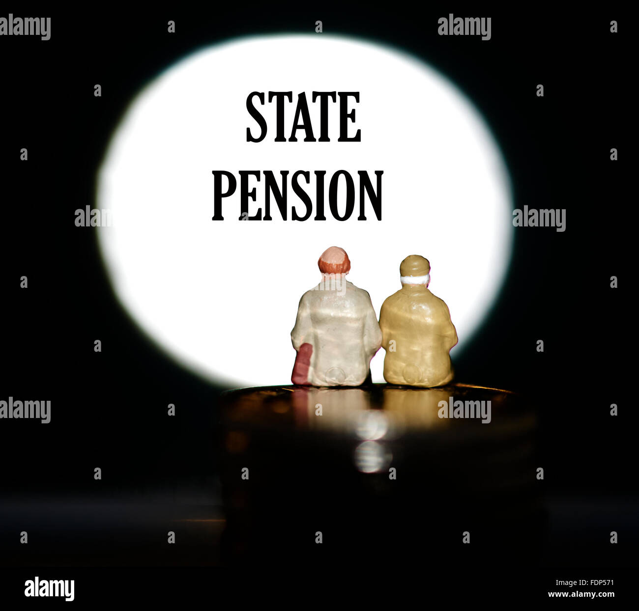 Statuetta in miniatura pensionati seduti sulle monete di fronte un faretto che mostra le parole di stato il concetto di pensione Foto Stock