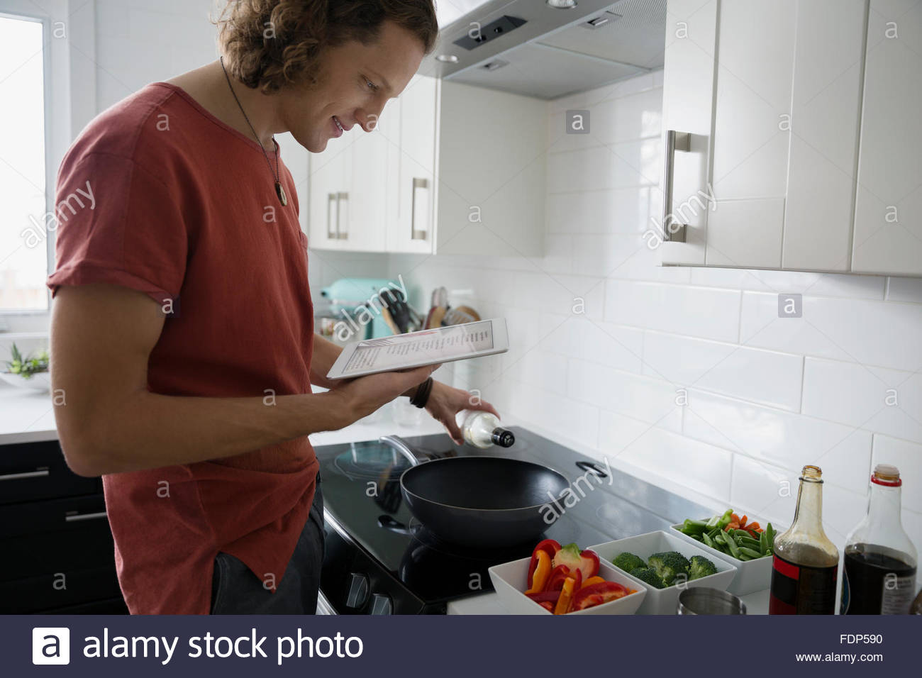 Uomo con tavoletta digitale per la cottura in cucina Foto Stock