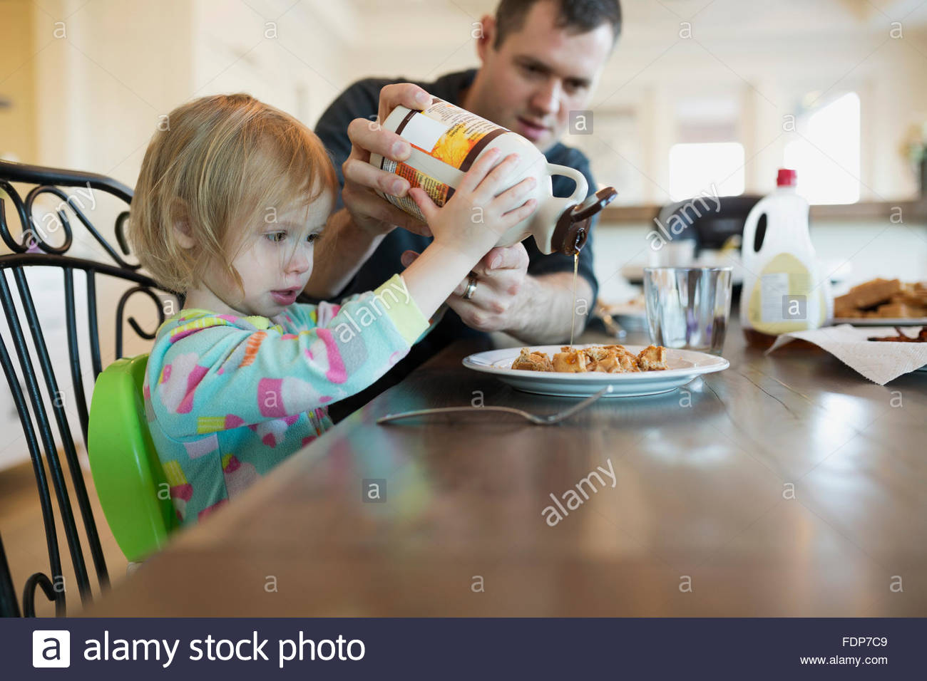 Padre aiutando la figlia Versare lo sciroppo d'acero in cialde Foto Stock
