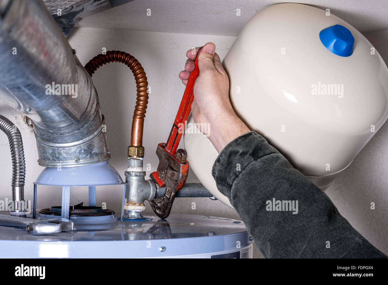 L'uomo lavora su un riscaldatore di acqua calda con una chiave a tubo Foto Stock