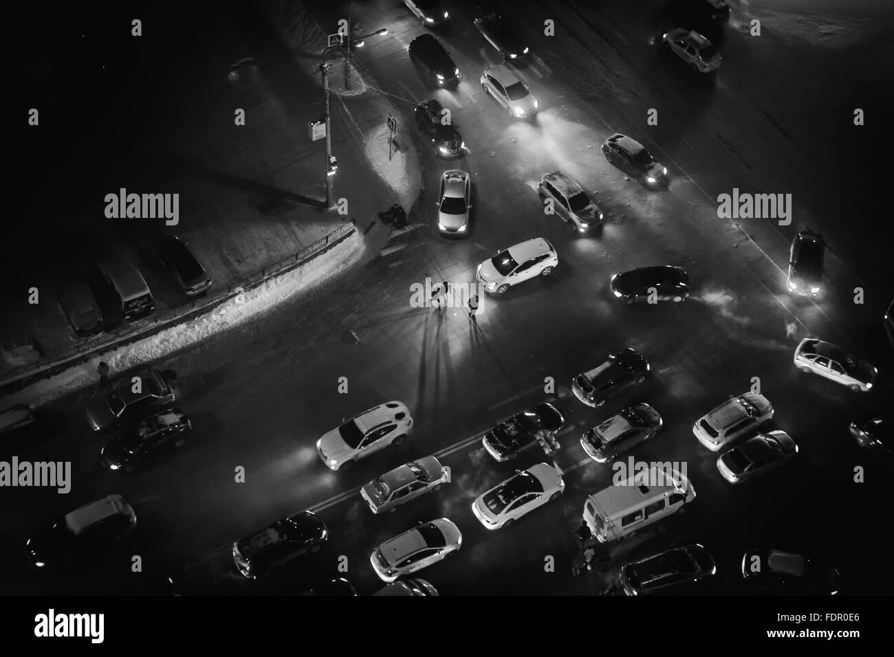 La gente di notte a piedi attraverso un passaggio pedonale in una città frenetica di traffico. Immagine monocromatica in bianco e nero. Copia dello spazio. Foto Stock