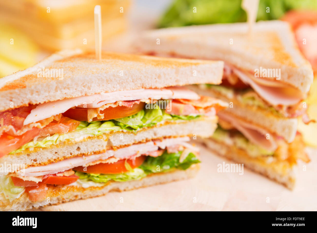 Un club sandwich su un tavolo rustico in condizioni di luce intensa. Foto Stock