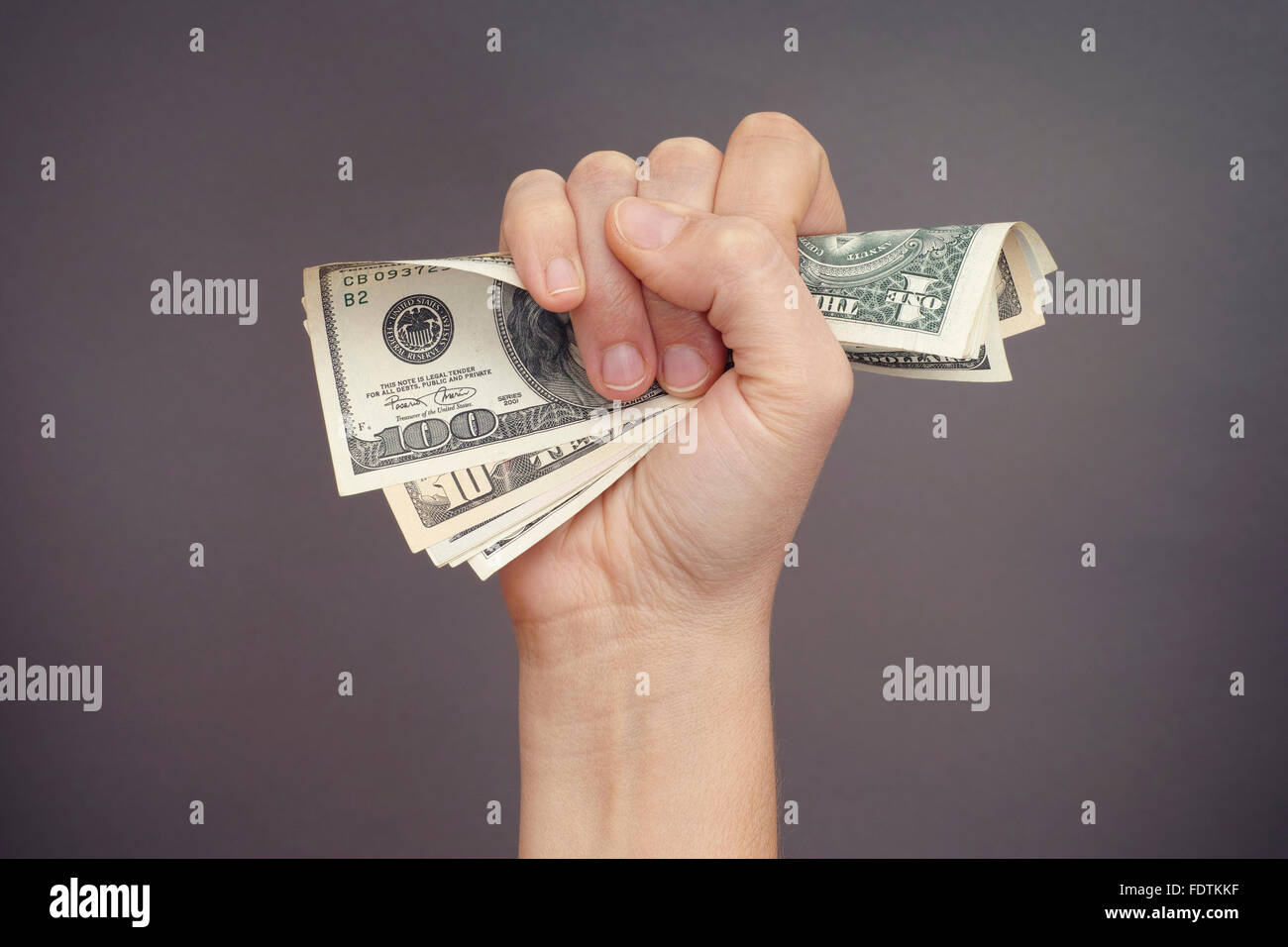 La donna si stringe a mano le fatture del dollaro contro uno sfondo grigio. Foto Stock