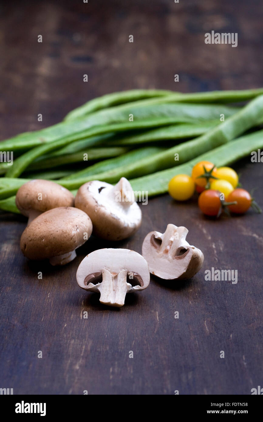 Funghi, pomodori e fagioli runner su una tavola di legno. Foto Stock