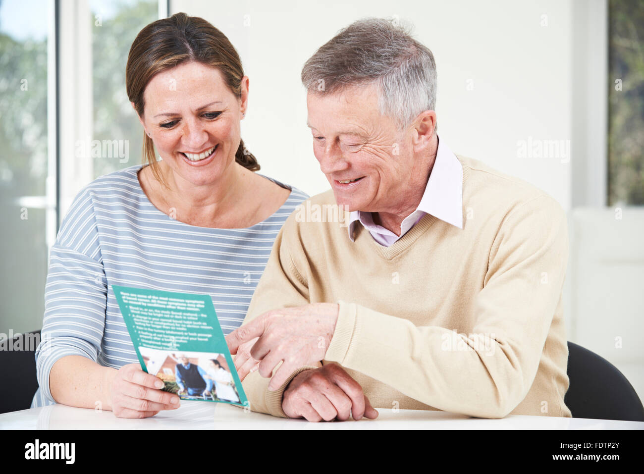 Senior l'uomo con la figlia adulta Guardando Brochure per casa di riposo Foto Stock