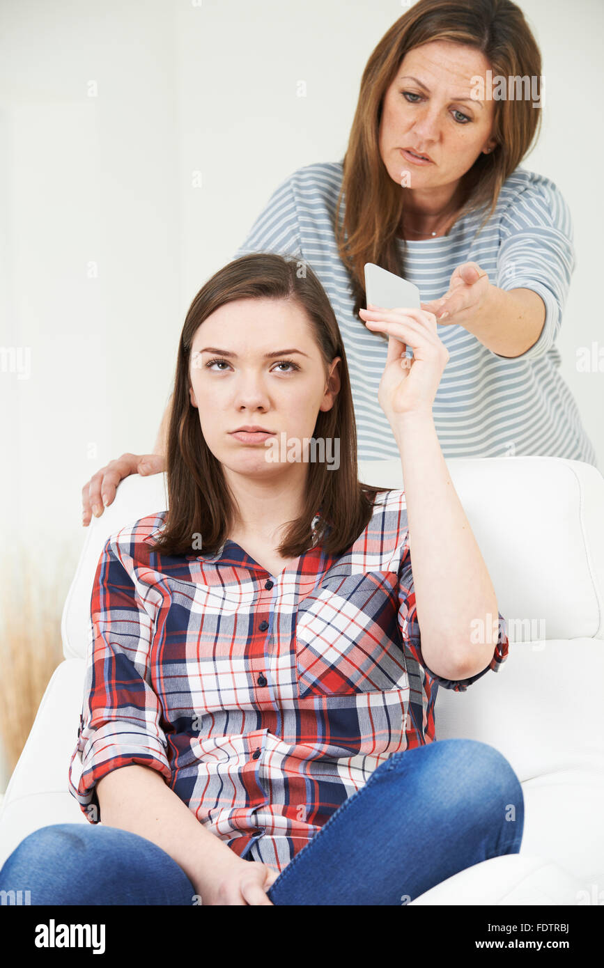 Madre tenendo il telefono cellulare lontano dalla figlia adolescente Foto Stock