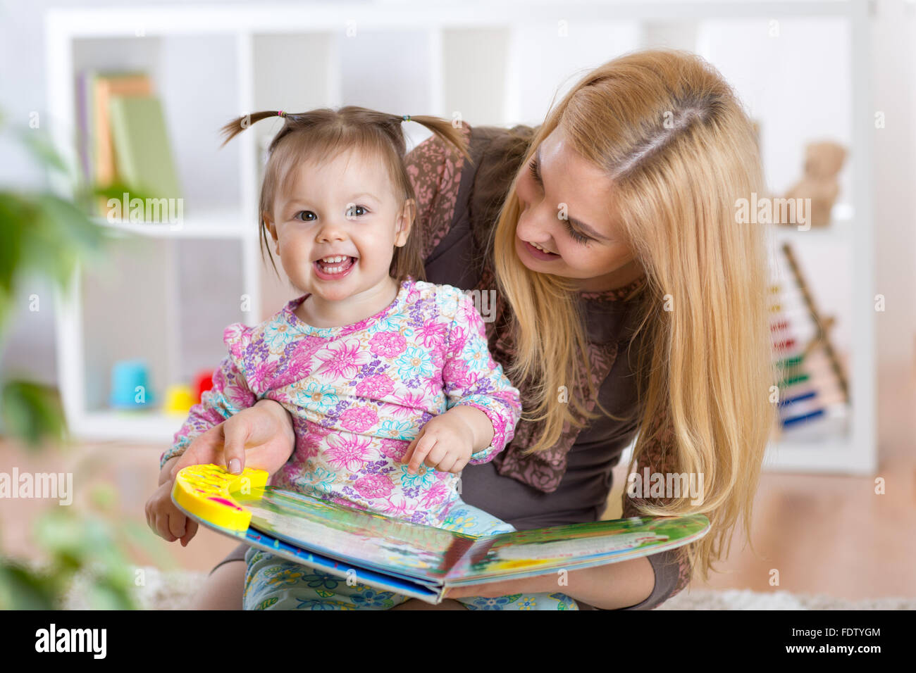 Felice giovane donna e bambino ragazza guardando un opuscolo per bambini Foto Stock
