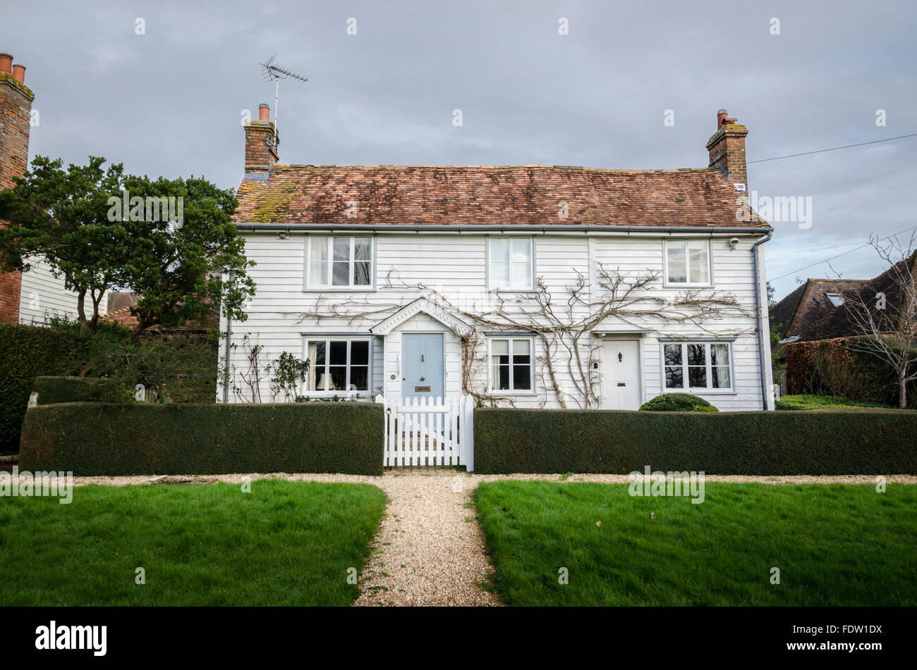 Piuttosto Bianchi infissi in legno cottage su un villaggio verde, Kent, Regno Unito Foto Stock