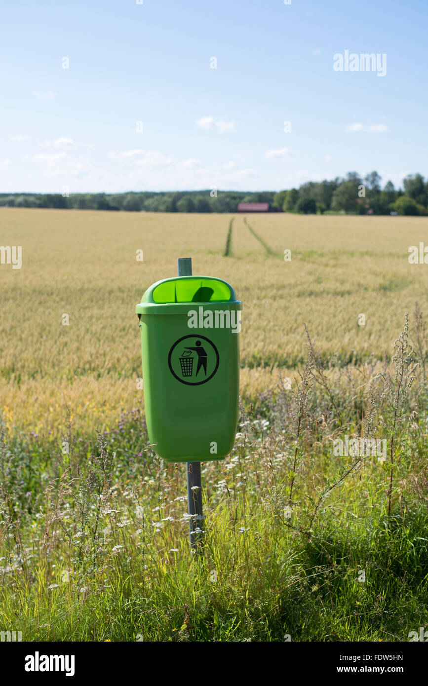 Cucciolata verde bin dal lato della strada con i campi in background Foto Stock
