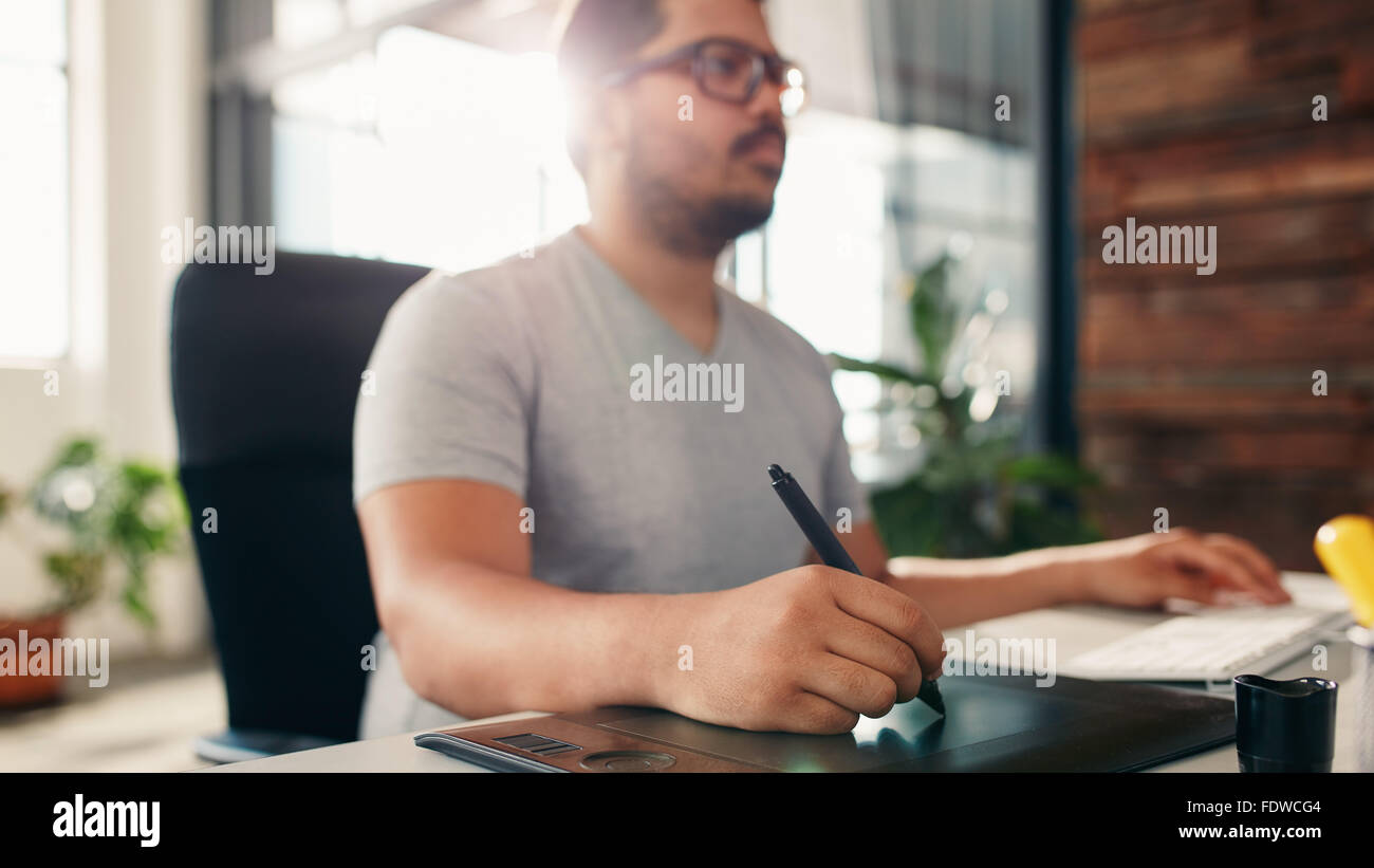 Immagine di un artista mani lavorando sulla tavoletta grafica presso l'ufficio. Graphic designer seduto alla scrivania e guardando il display. Foto Stock