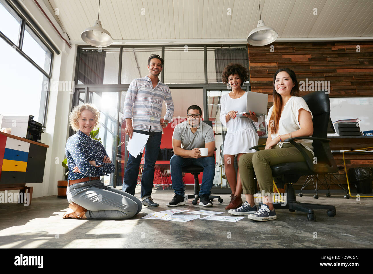 Ritratto di felice i giovani in un incontro guardando la fotocamera e sorridente. I giovani designer che lavorano insieme su un progetto creativo Foto Stock