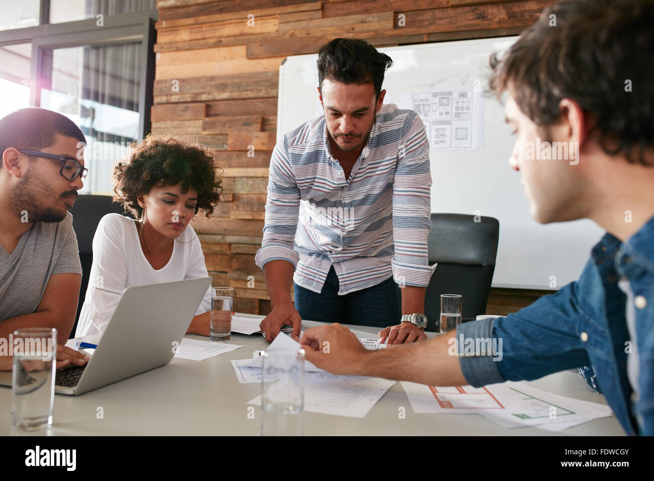 Giovane uomo a discutere di una ricerca di mercato con i colleghi in una riunione. Team di giovani professionisti aventi un Incontro in conferenza ro Foto Stock