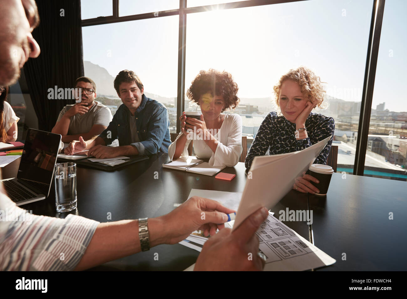 Primo piano delle mani del giovane maschio discutendo executive business plan con i colleghi. Le persone creative che incontro in sala conferenze. Foto Stock