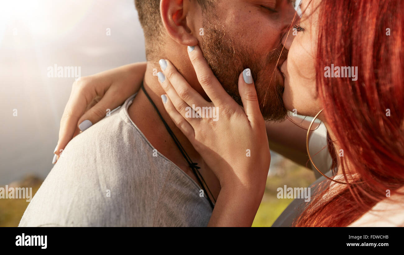 Immagine ravvicinata di amorevole coppia giovane kissing all'esterno. L uomo e la donna baciare ogni altro romanticamente cercando con molto amore. Foto Stock