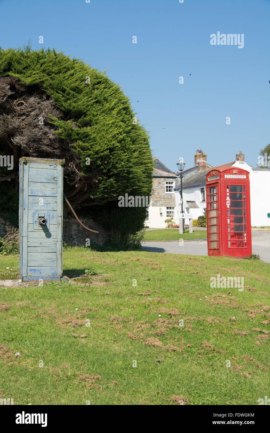 La vecchia pompa acqua e il telefono rosso scatola nel pittoresco villaggio di cappella camminare, North Cornwall Foto Stock