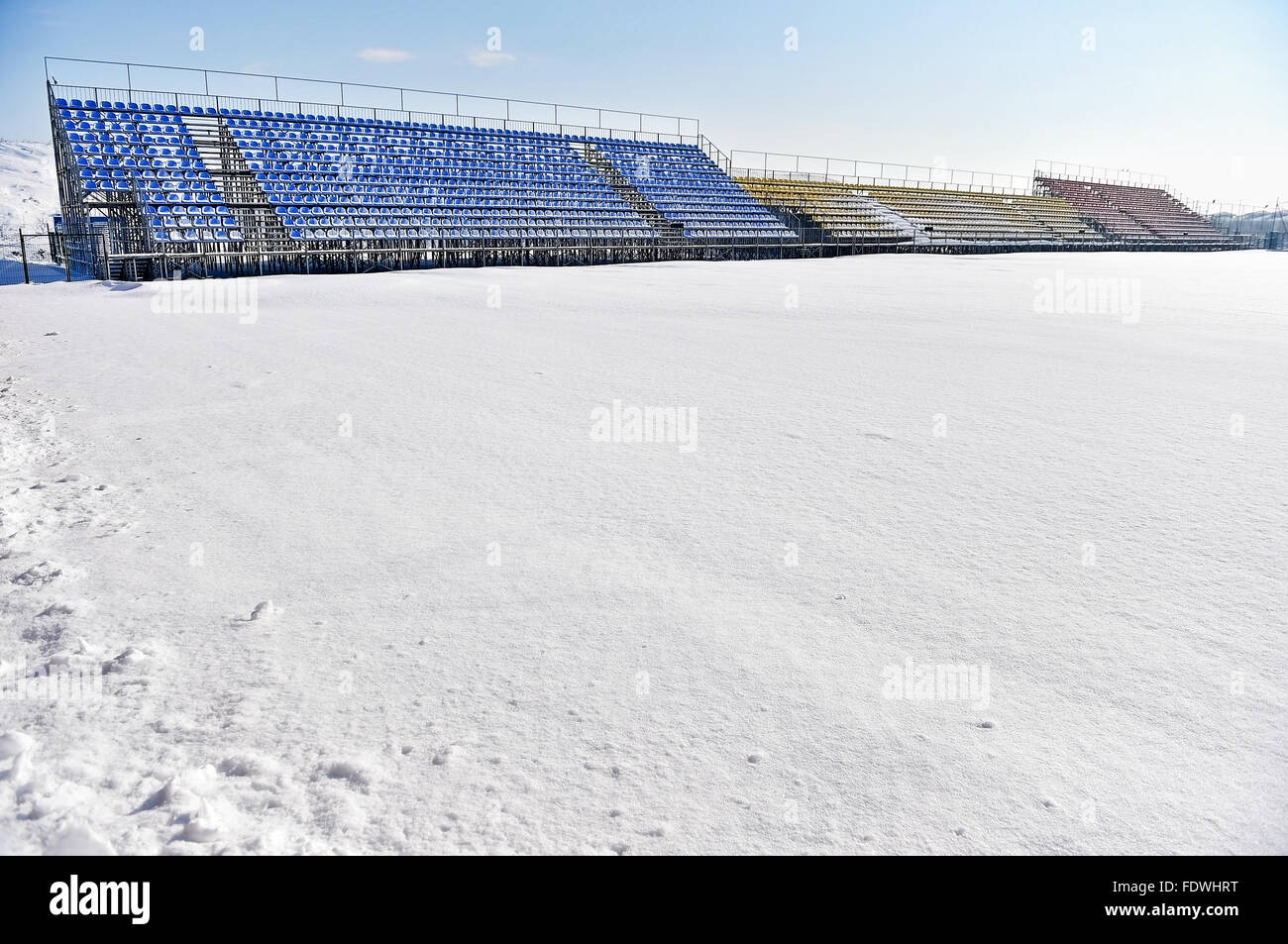 Tribune vuote e di uno stadio di calcio coperto di neve dopo una nevicata Foto Stock