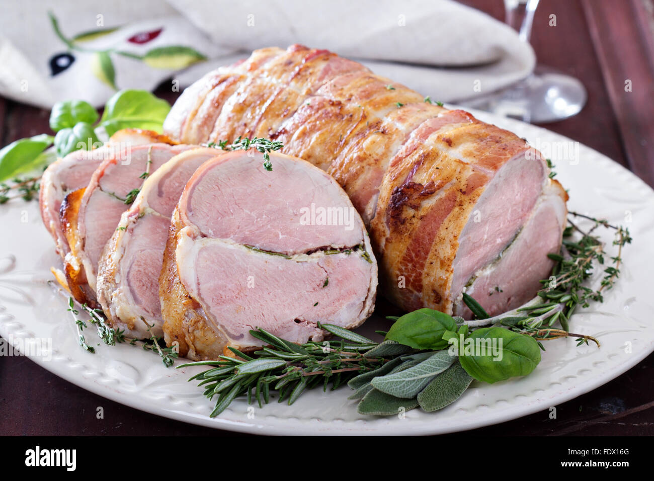 Arrosto di maiale con aglio cotto al forno, erbe e pancetta Foto Stock