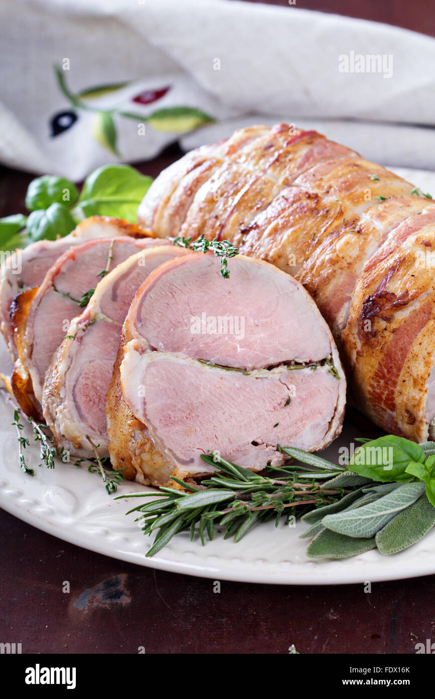 Arrosto di maiale con aglio cotto al forno, erbe e pancetta Foto Stock