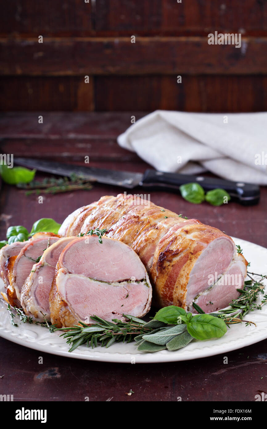 Arrosto di maiale con aglio cotto al forno, erbe e pancetta Foto Stock
