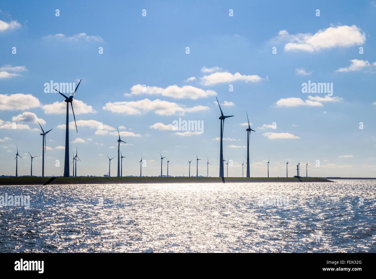 Wind Farm sulla costa retroilluminati da il sole al Eemshaven seaport, Groningen, Paesi Bassi Foto Stock