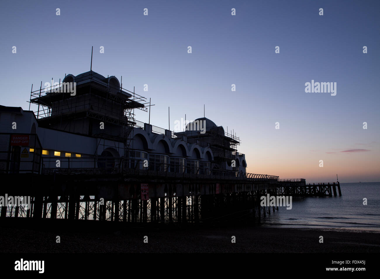 Sunrise dietro South Parade pier a Southsea. Fredda mattina fresco risultante in un bagliore di formatura e riflettendo in mare. Foto Stock