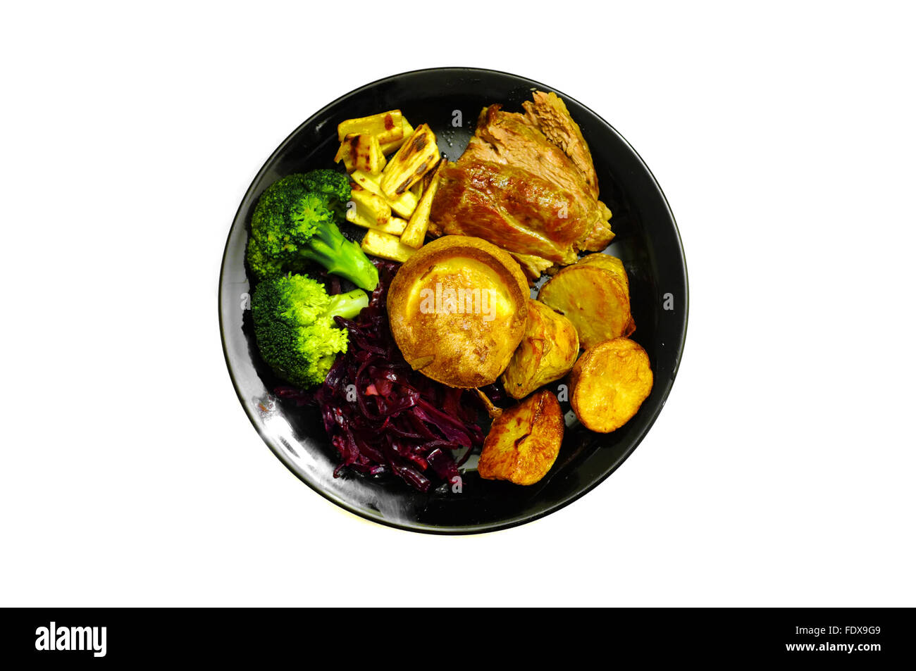 Un arrosto con tutti i ritagli su una piastra nera fotografati contro uno sfondo bianco Foto Stock