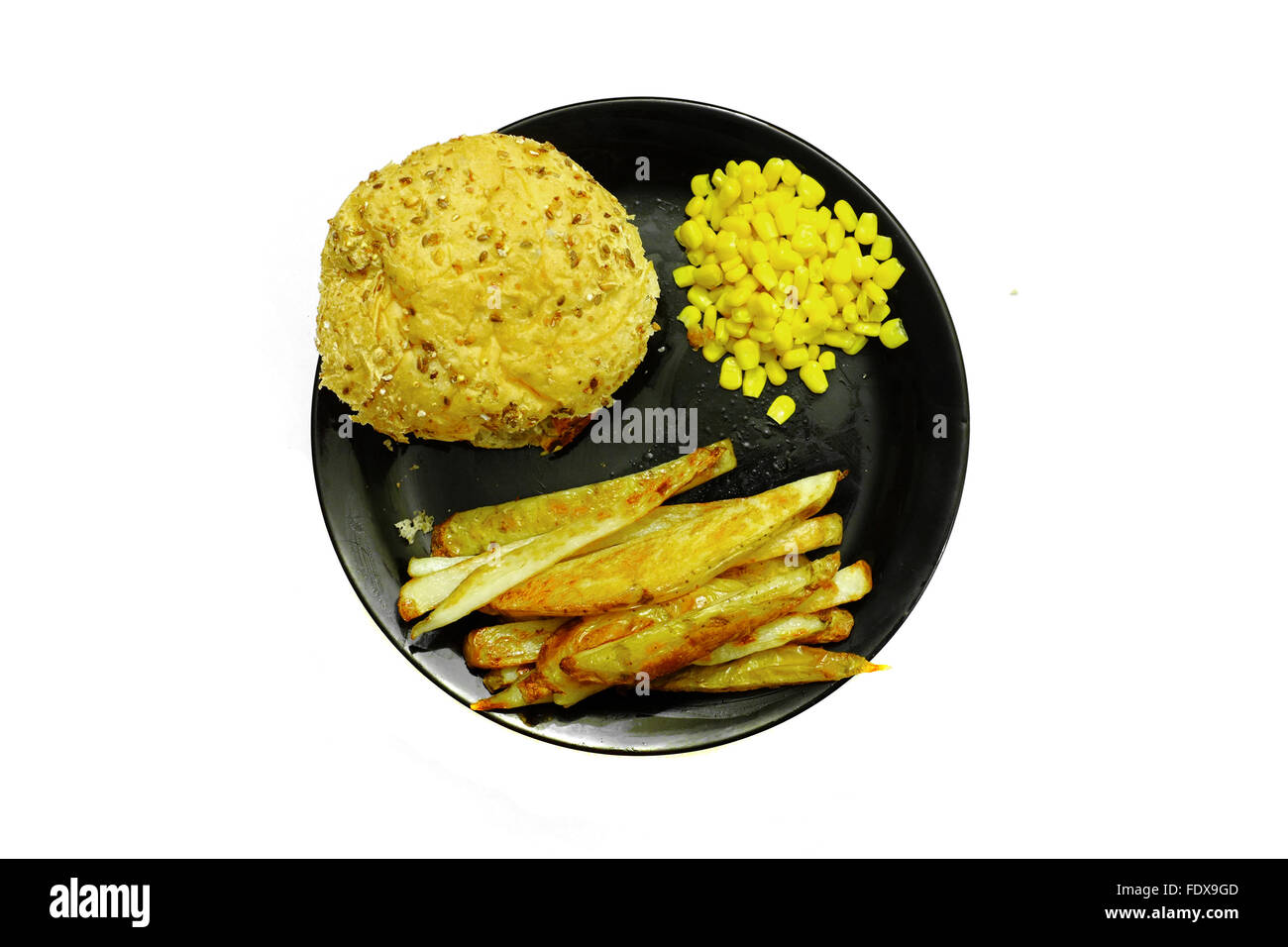 Una piastra di hamburger, patatine e il granturco dolce su una piastra nera fotografati contro uno sfondo bianco Foto Stock