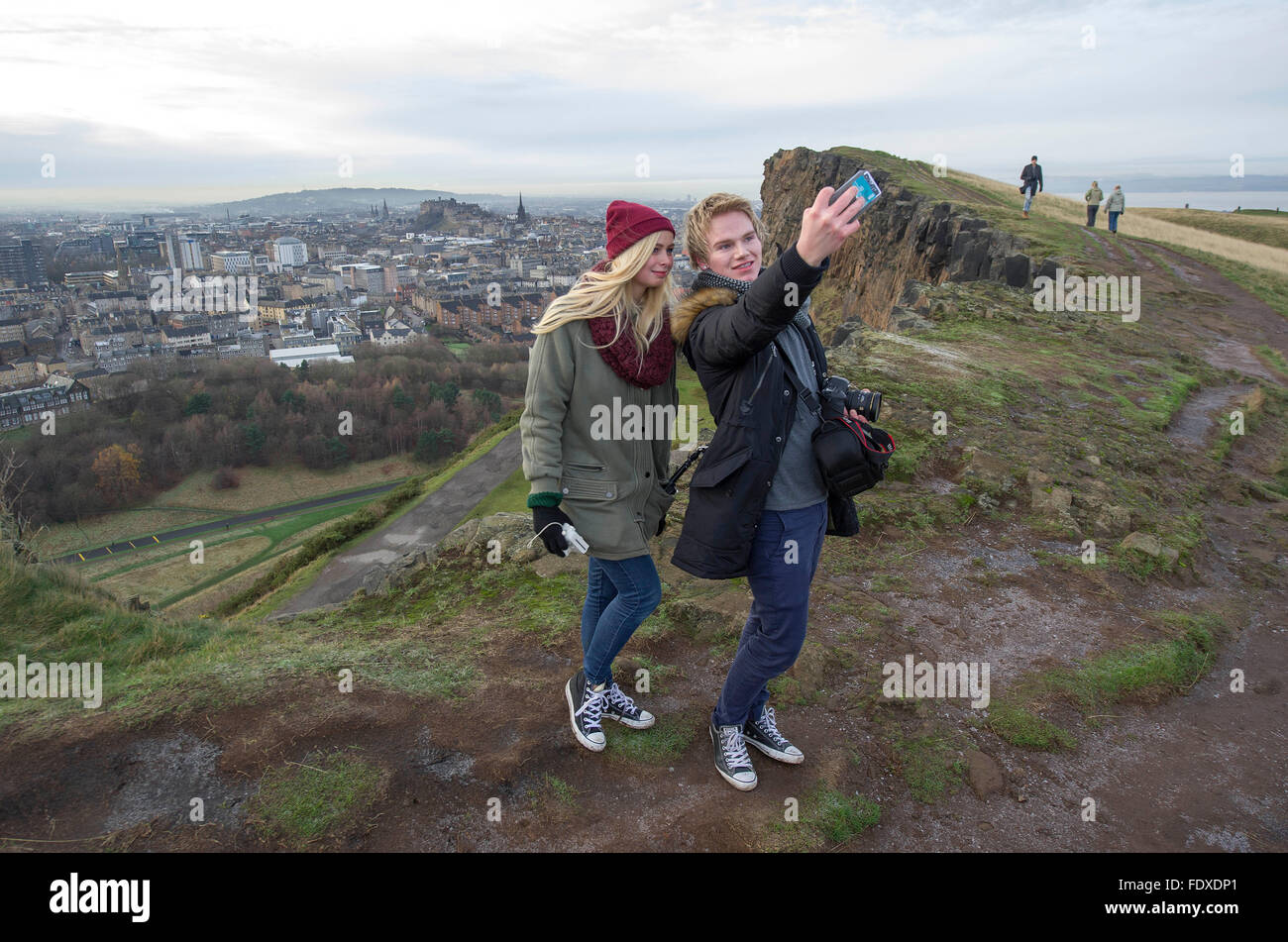 Edimburgo, Scozia, Regno Unito. Gli studenti norvegesi prendere un selfie su Salisbury Crags Holyrood Park con il Castello di Edinburgo e la città vecchia come sfondo. Foto Stock