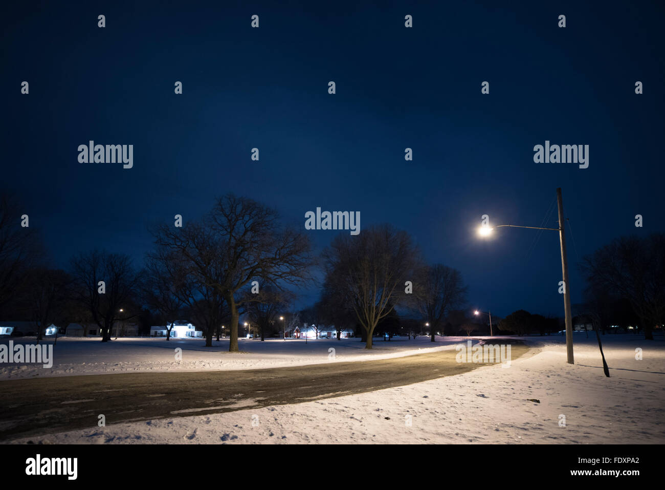Lampione illumina la strada e la neve di notte. Foto Stock