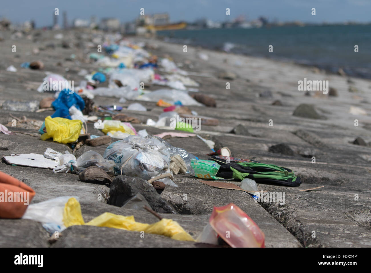 La marea si ritira lasciando una linea spessa principalmente di immondizia di plastica lungo il canale di spedizione le principali banche al Porto di Cebu. Foto Stock
